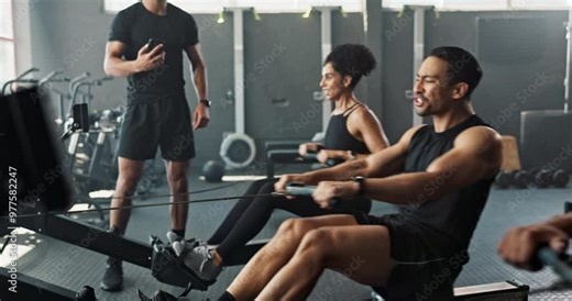 Workout, rowing machine and instructor with group in gym for wellness, sports or body health. Coach, club and people exercise on ergometer for fitness, muscle and cross training for cardio with pain