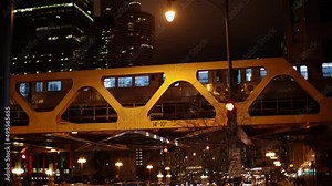 CTA Train passing over River on Elevated Track at Night. Train cars illuminated inside. Subway in Chicago